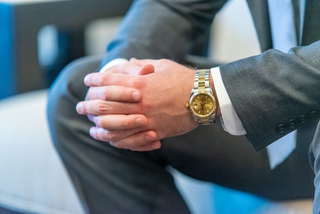 shallow focus shot of a man in suit clasping his hands with a blurred background
